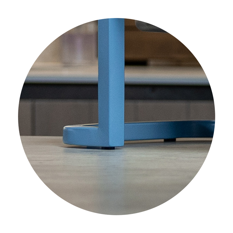 Close-up of a blue Better Bowl metal frame on a reflective surface.. Weighted, non-slip base. Stays where you want it to stay.